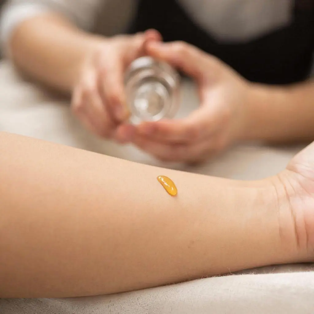 A person performing a patch test by applying a small drop of propolis to their inner forearm.